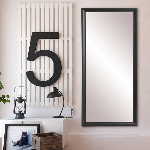 A BrandtWorks matte black mirror hanging on a white wall.