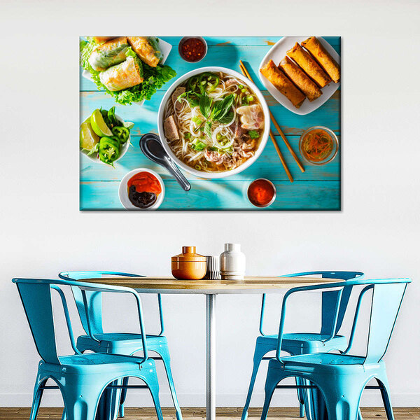 A table with blue chairs and a Vietnamese feast canvas on the wall above it.