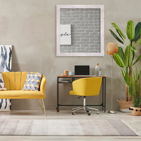A cream farmhouse grain finish mirror reflecting a yellow couch with a pillow and a yellow chair with wheels in a living room.