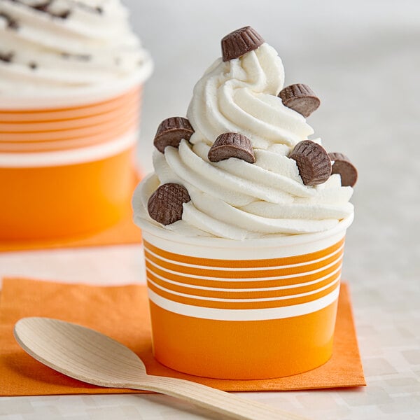 Two cups of frozen yogurt with a wooden spoon.