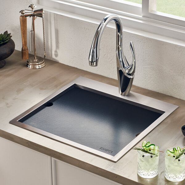 A Ruvati stainless steel drop-in workstation sink with a black faucet and glasses of water.