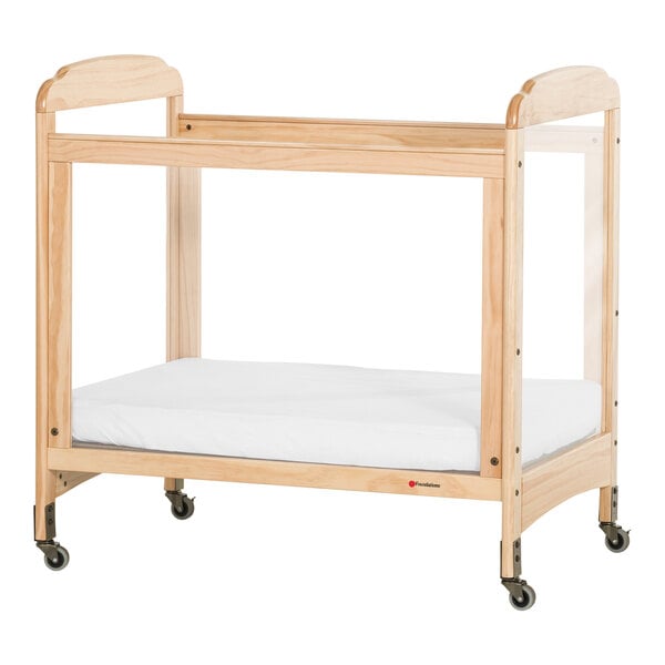 A Foundations Next Gen wooden crib with clear panels and a mattress inside.
