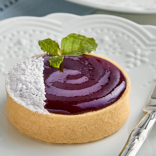 A pastry filled with Crofter's Organic Concord Grape Jelly next to a knife on a plate.