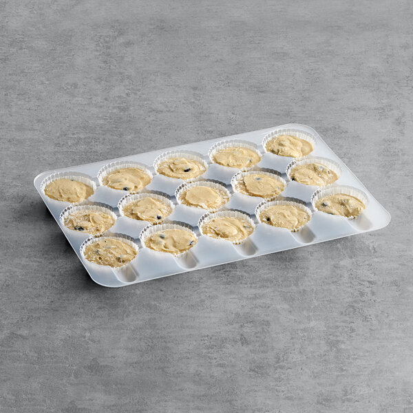 A tray of muffins with dough in them.