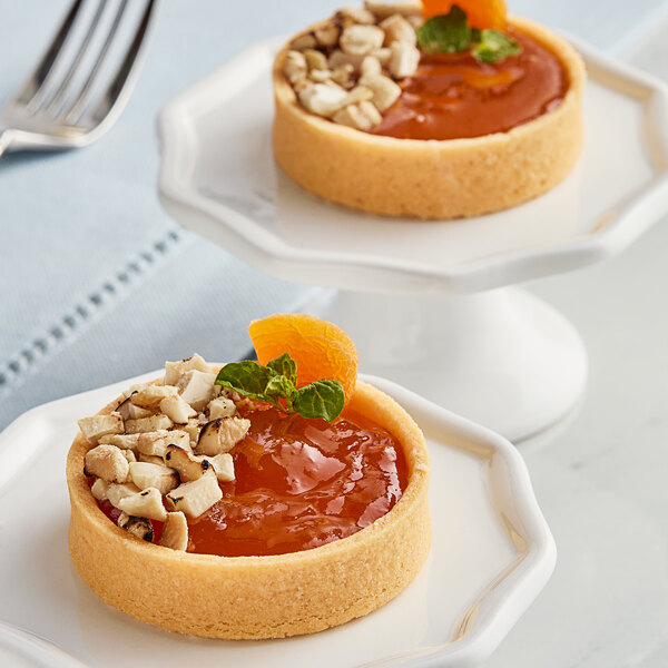 Two small pastries with Crofter's Organic Apricot Preserves, fruit, and nuts on a plate.