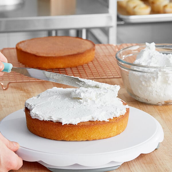 A person spreading Brill vanilla topping on a cake.