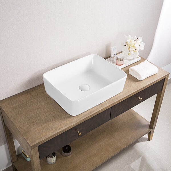 A Ruvati white rectangular above-counter sink on a wood table.