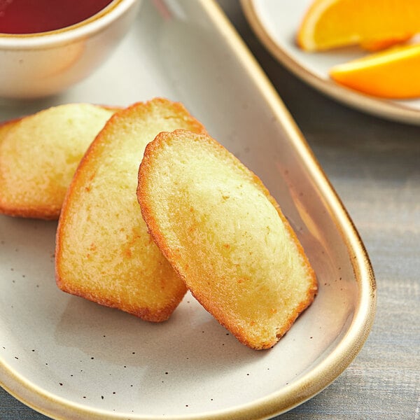 A plate with St. Michel Citrus Madeleines and orange slices on a table.