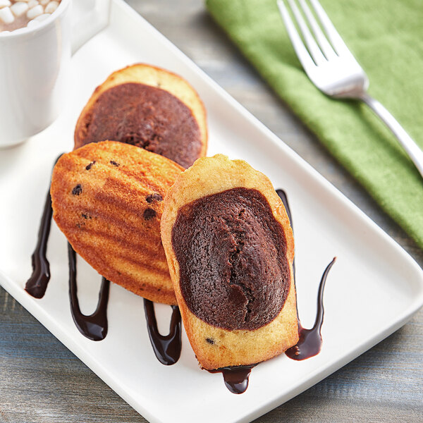A plate of St. Michel Chocolate Marble Madeleines with chocolate sauce.