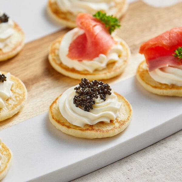 A group of Le Chic Patissier mini blinis topped with cream cheese and fish.