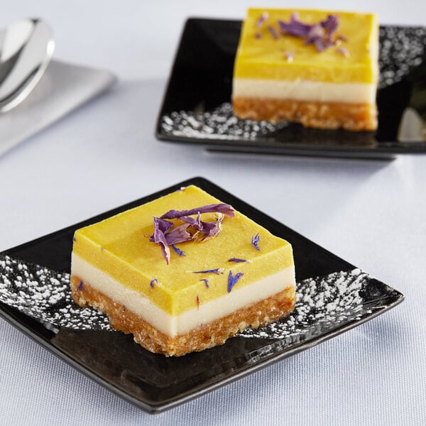 Two square yellow and white Nats Rawline plant-based vegan desserts with purple petals on top.