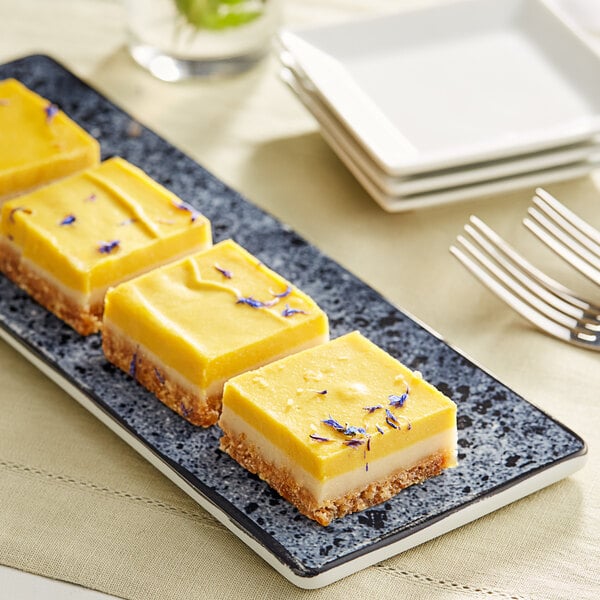 A plate of Nats Rawline lime and mango raw cake squares on a table.