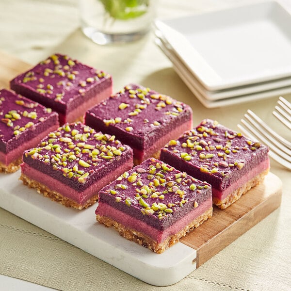 A plate with twelve Nats Rawline plant-based vegan raspberry and blueberry raw cake squares.