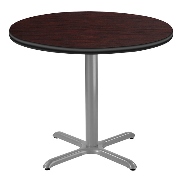 A National Public Seating round table with a mahogany wood top and gray metal X base.