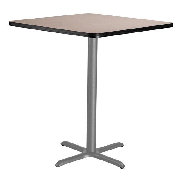 A square National Public Seating bar height table with a gray wooden top and metal X base.