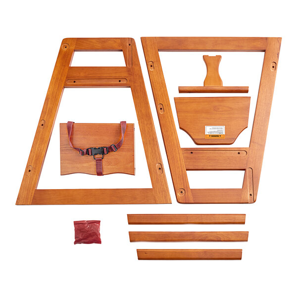 A Lancaster Table & Seating wooden high chair with a red strap on a wood surface.