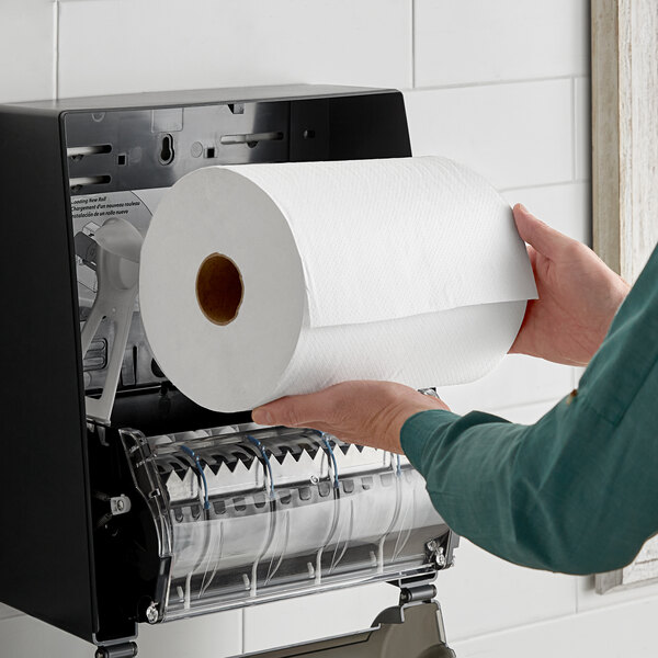 A hand holding a Morcon Morsoft white hardwound paper towel roll.