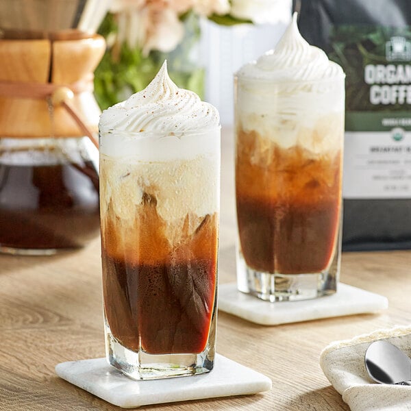 A cup of Crown Beverages organic whole bean coffee with ice on a table.