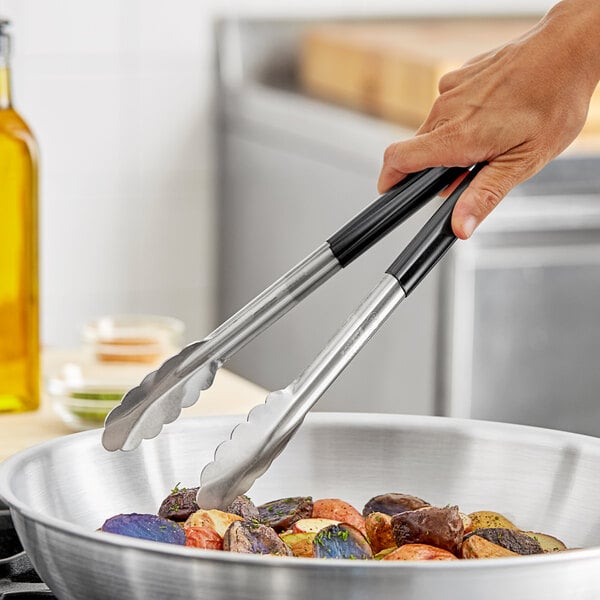 A person using Fourté black stainless steel scalloped tongs to serve food.