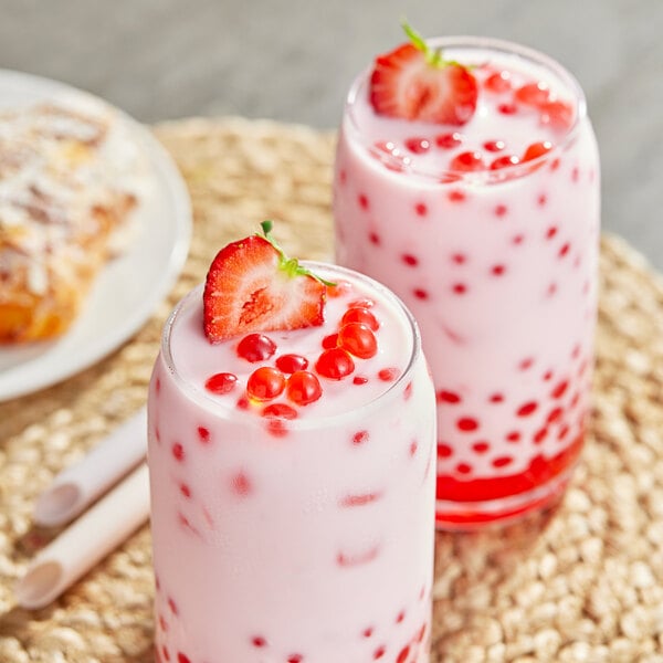 A glass of milk with red Bossen strawberry bursting boba.