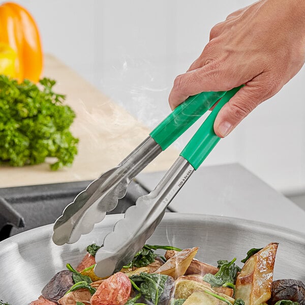 A person using Fourt&#233; green stainless steel scalloped tongs to serve food.