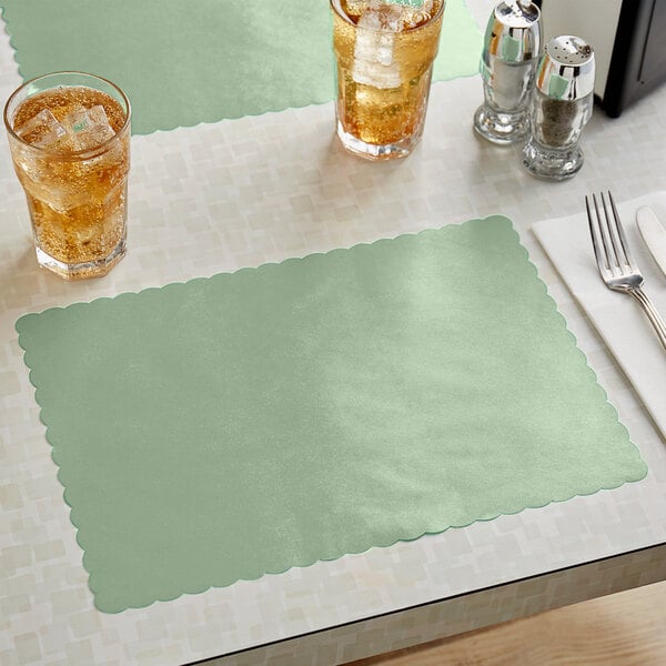 A sage green scalloped paper placemat on a table with glasses of ice tea.