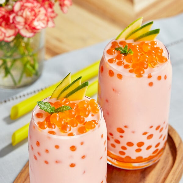 Two glasses of pink milkshake with Bossen mango bursting boba on top.