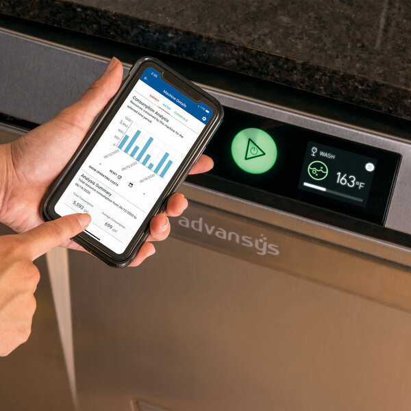 A high temperature undercounter dishwasher with energy recovery, shown with a person using a smartphone to monitor its performance.