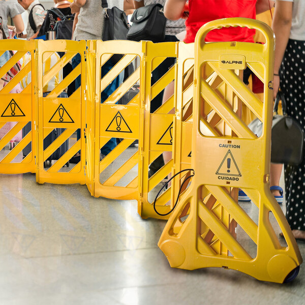 A group of people standing in a line with yellow Alpine mobile barriers.
