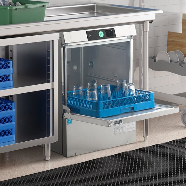 A commercial undercounter dishwasher with a blue rack holding glassware, installed beneath a stainless steel countertop.