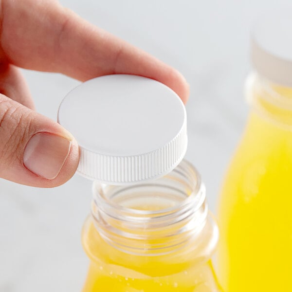 A hand holding a 38/400 white plastic cap over a bottle.