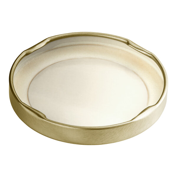 A gold metal lid with a white plastisol liner on a white background.