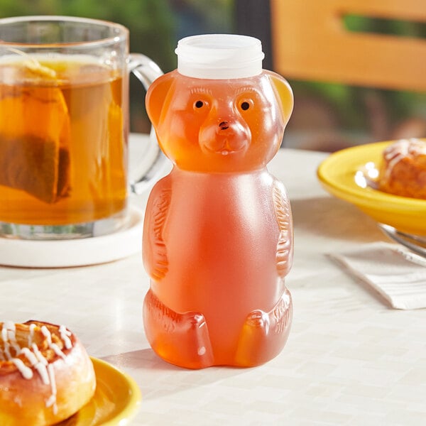 A plastic bear shaped container of honey on a table.