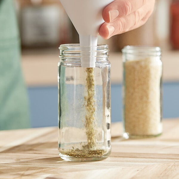 A person's hand pouring salt into a Paragon glass jar.