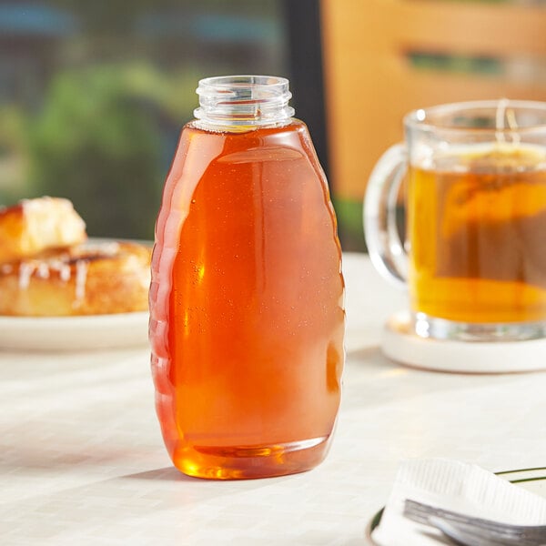 A Classic Queenline PET inverted honey bottle on a table with honey inside.