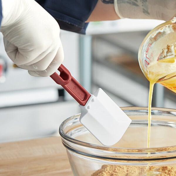 A person using a Vollrath silicone spatula to mix batter in a bowl.