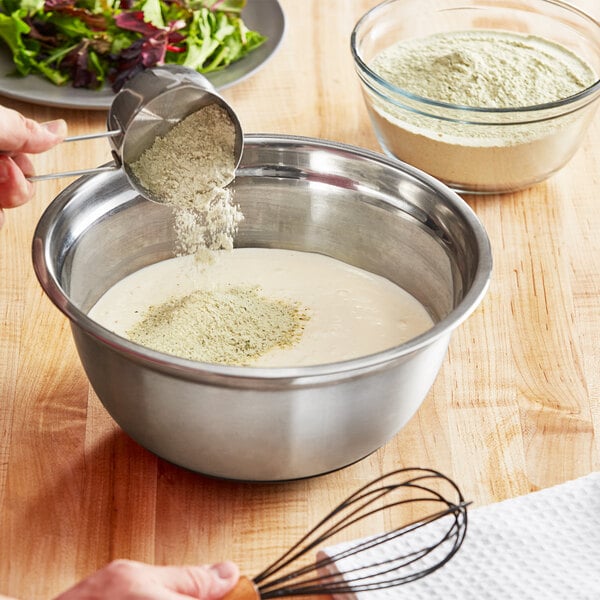 A person pouring Foothill Farms Ranch Dressing Mix into a bowl of food.