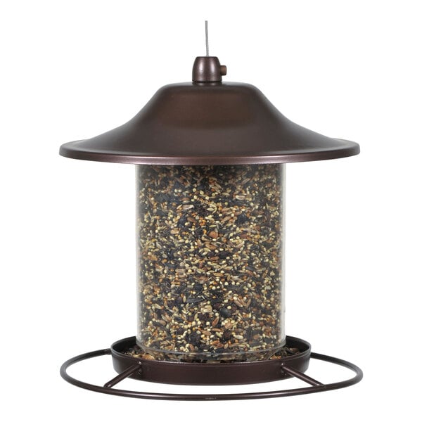 A Perky-Pet bird feeder with seeds in it on a brown metal base.