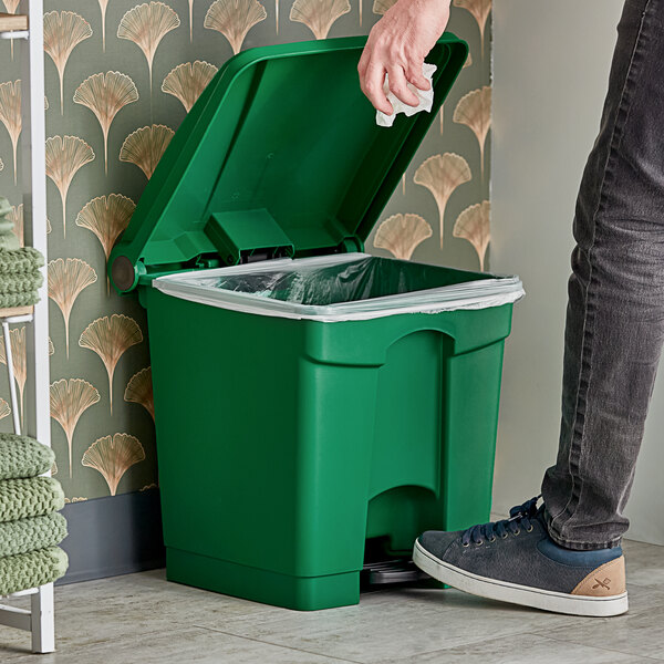 A person standing next to a Lavex green rectangular step-on trash can.