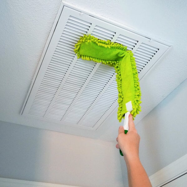 A green flexible microfiber wand duster being used to clean a ceiling vent.
