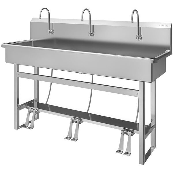 A stainless steel Sani-Lav floor-mounted multi-station utility sink with foot-operated faucets.