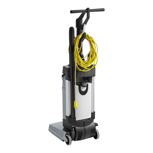 An Advance SC100 walk behind floor scrubber with a yellow cord and wand.