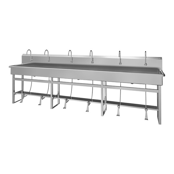 A large stainless steel floor-mounted utility sink with 6 foot-operated faucets.