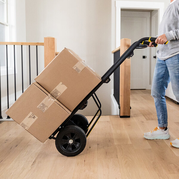 A person using a Gorilla steel hand truck to move boxes.