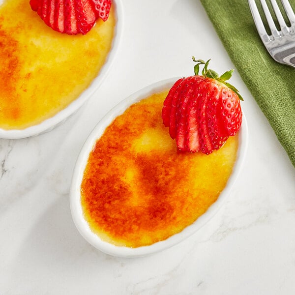 A bowl of dessert with strawberries on top.