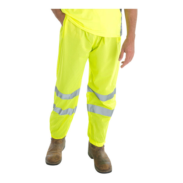 A man wearing Cordova Hi-Vis lime yellow mesh pants with reflective tape.