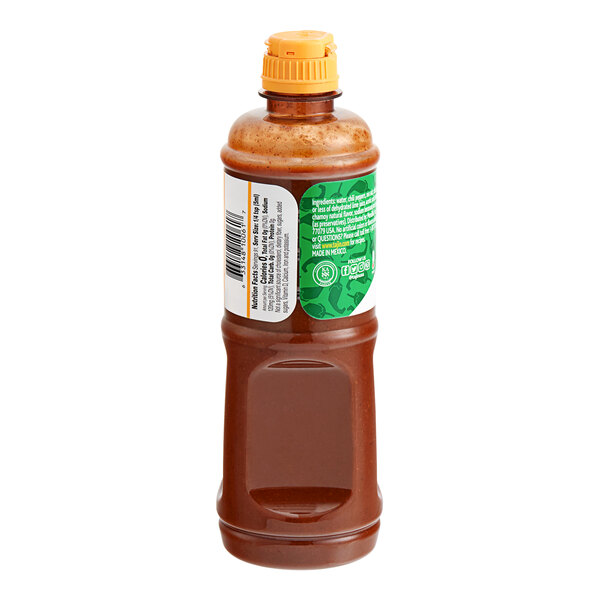 A close up of a bottle of Tajin Chamoy Hot Sauce with a brown liquid inside and a white lid.