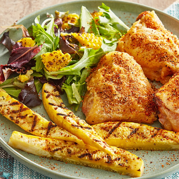 A plate of food with grilled chicken and Tajin seasoning on a table.