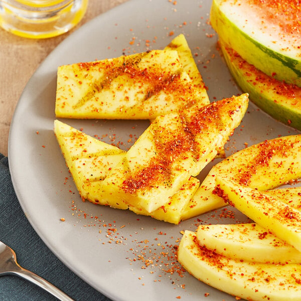 A plate of pineapple and melon slices with Tajin seasoning.