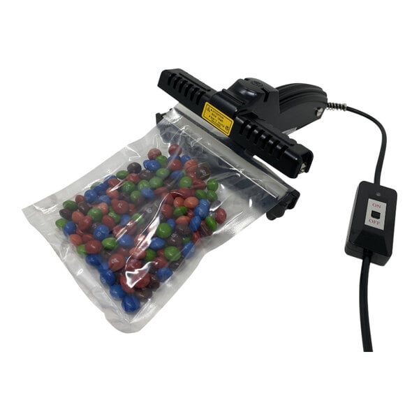 A Sealer Sales portable poly sealer sealing a plastic bag of candy next to a cord.